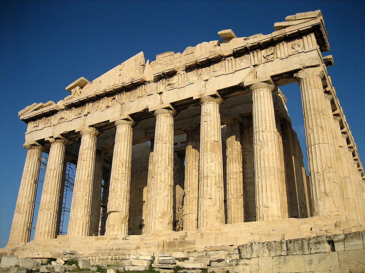 The Parthenon, a ruined marble temple with rows of columns, under a blue sky