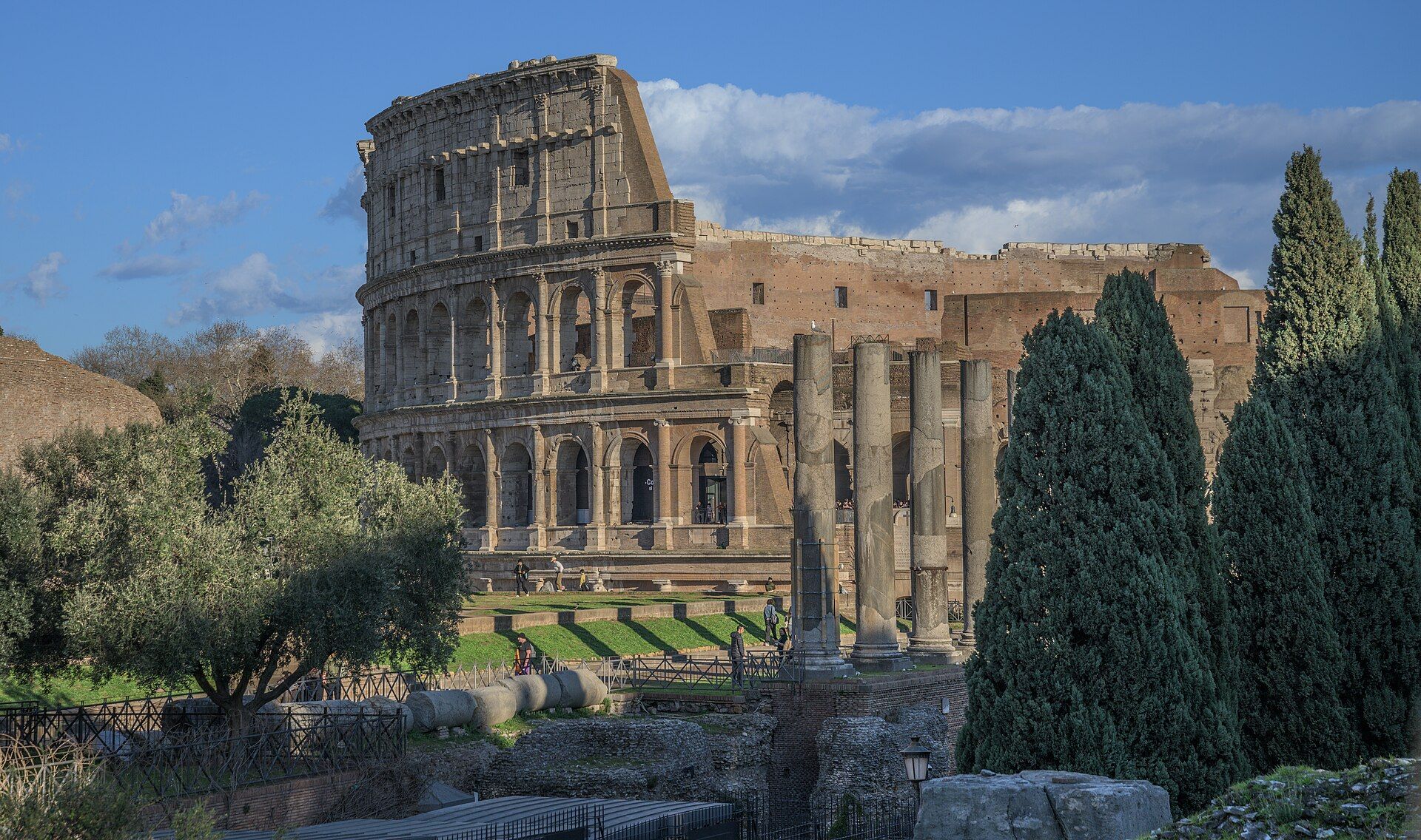 The Colosseum in Rome, a huge oval stone arena, with trees in front