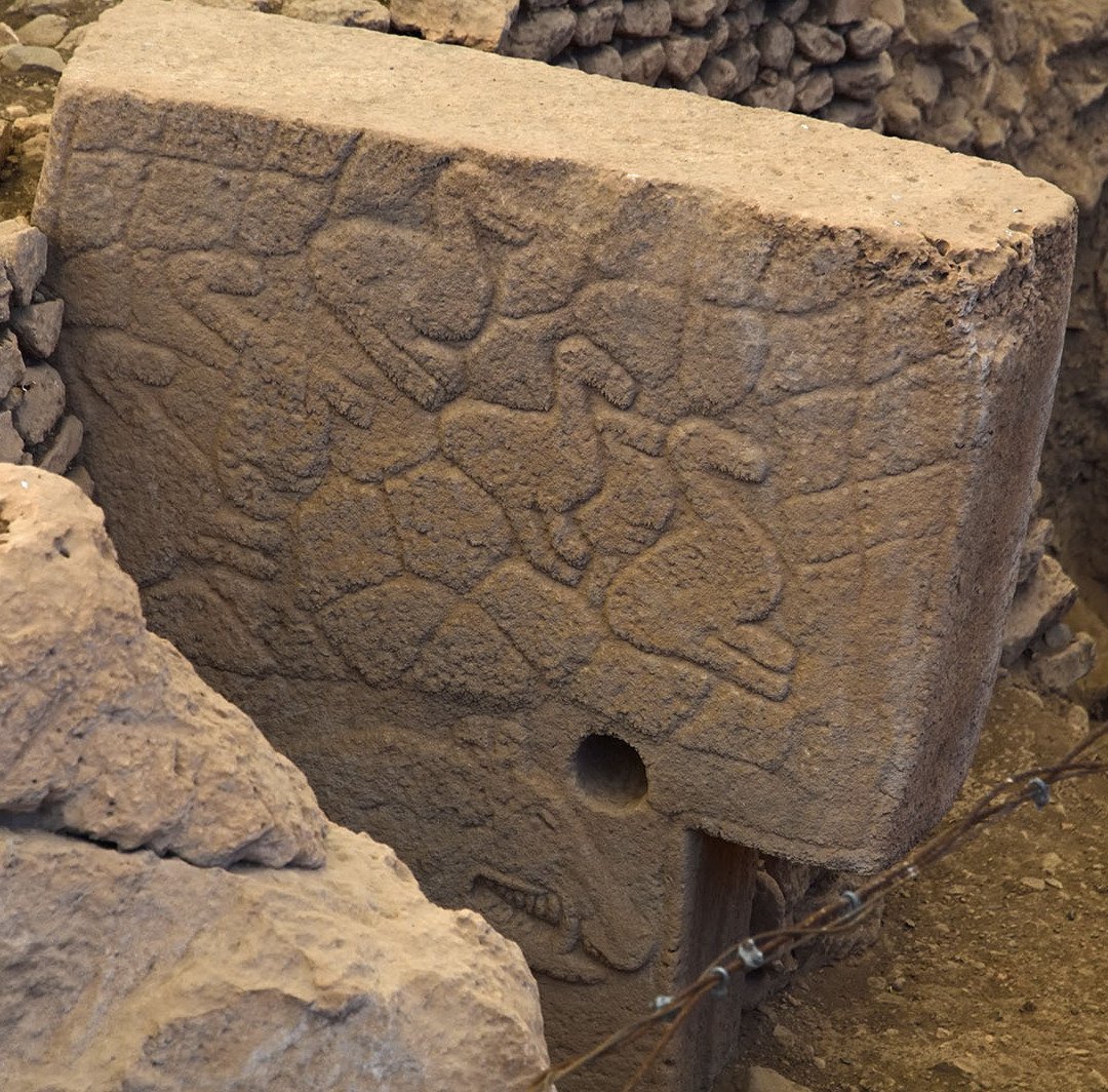 Animals carved in relief on the side of a large stone pillar