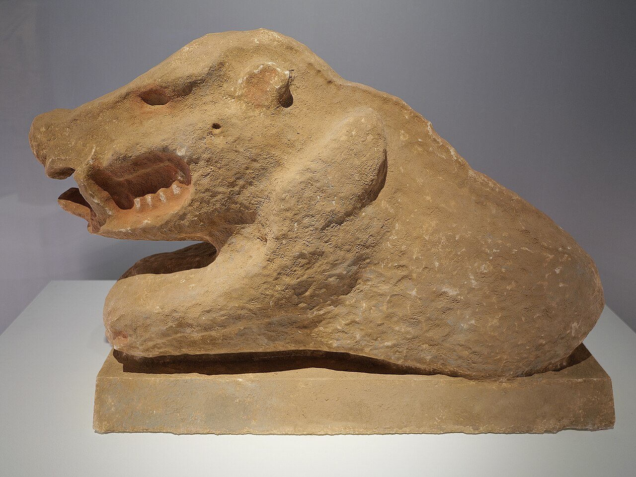 A stone statue of a wild boar with an open mouth and sharp teeth