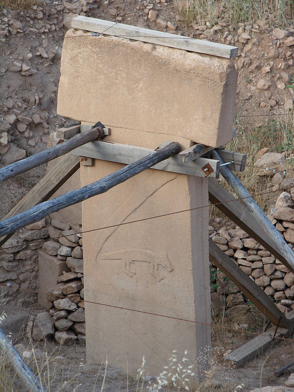 A T-shaped stone pillar with a long carved arm on its side and a carved fox below it